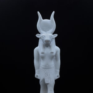 May include: White statue of an Egyptian god with a bull's head, standing on a base with hieroglyphs.