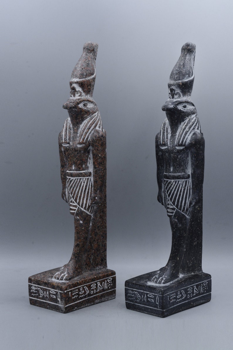 K&ouml;nnte beinhalten: Zwei Statuen aus schwarzem und braunem Granit des &auml;gyptischen Gottes Horus, die jeweils auf einem Sockel mit Hieroglyphen stehen. Die Statuen sind etwa 25 cm hoch.