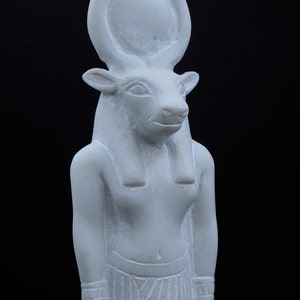 May include: White marble statue of an Egyptian god with bull horns and a human body.
