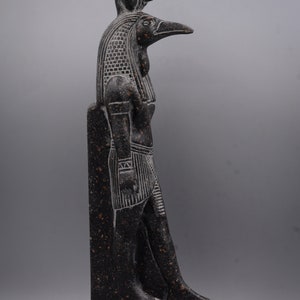 Puede incluir: Estatua de granito negro del dios egipcio Horus, representado como un hombre con cabeza de halc&oacute;n con un cuerpo humano y una cabeza de halc&oacute;n. La estatua est&aacute; de pie sobre una base rectangular con jerogl&iacute;ficos.