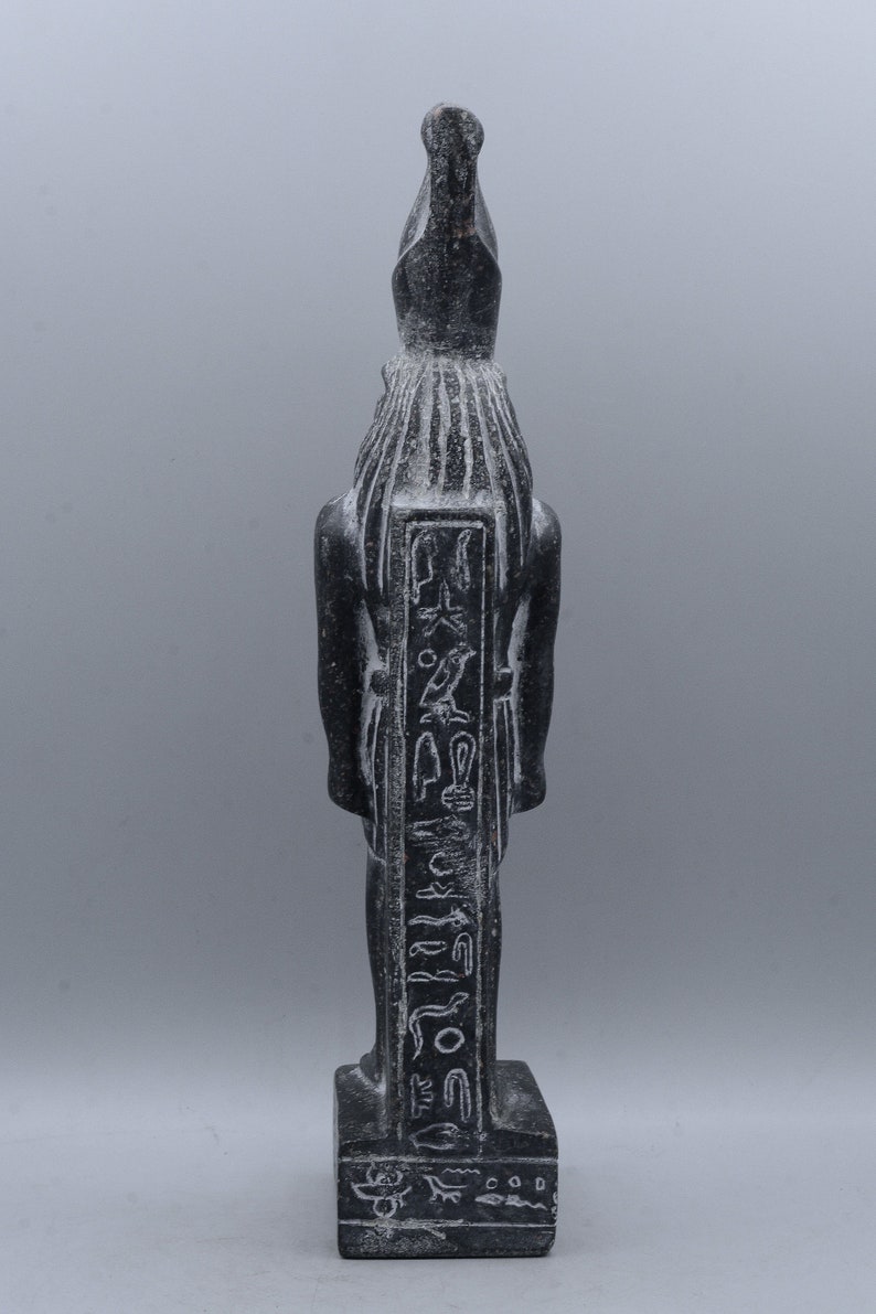 K&ouml;nnte beinhalten: Schwarze Steinstatue eines &auml;gyptischen Gottes mit Hieroglyphen, die auf die Vorderseite geschnitzt sind. Die Statue steht auf einem rechteckigen Sockel.