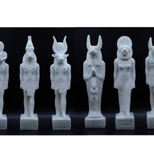 May include: Set of six white Egyptian god statues with different animal heads, including a ram, a jackal, a bull, a falcon, a lion, and a baboon. The statues are standing on rectangular bases with hieroglyphics.