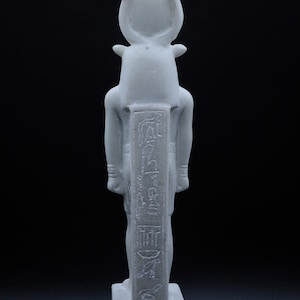 May include: White marble statue of the Egyptian god Apis, depicted as a bull with a human head. The statue is standing on a rectangular base and has hieroglyphs carved on the front.