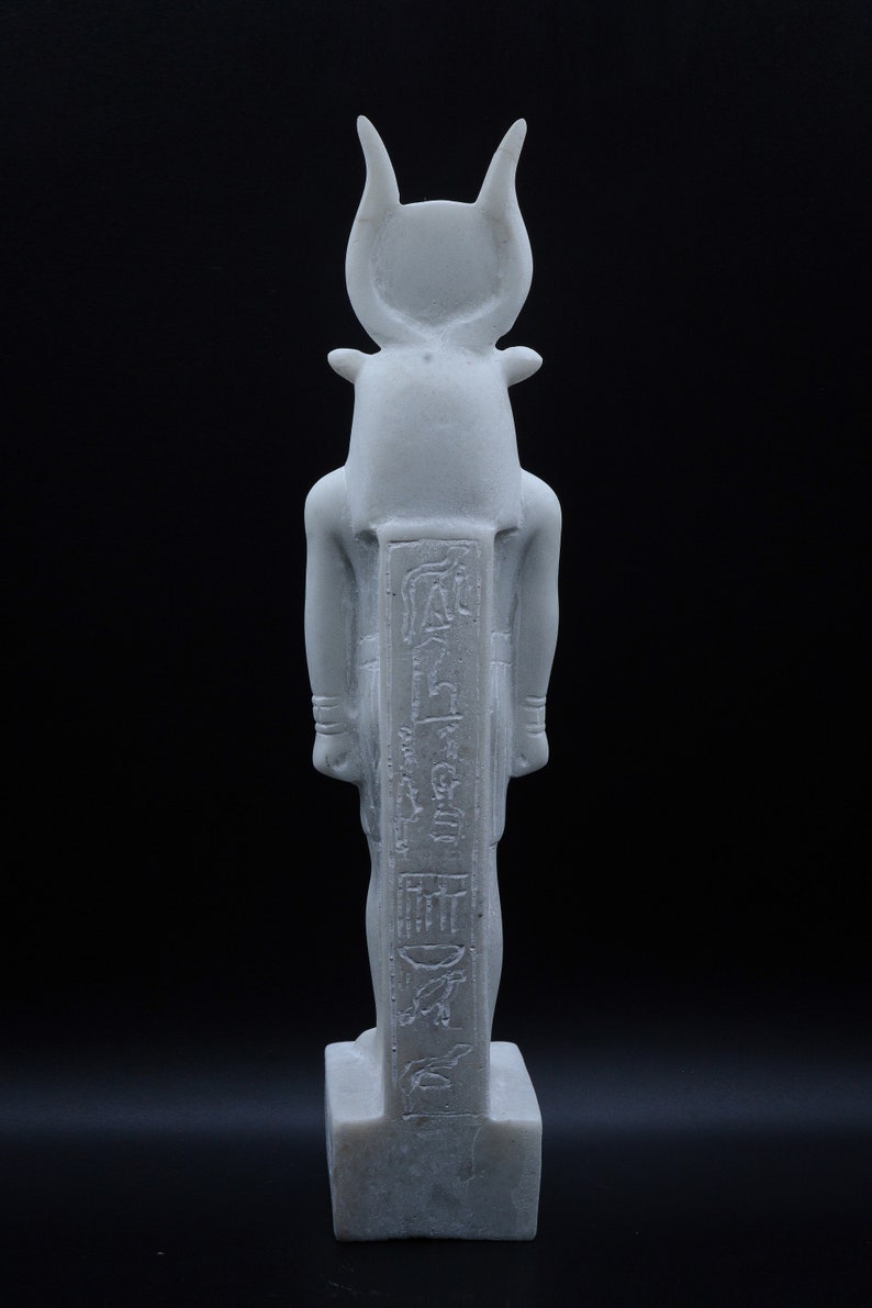 May include: White marble statue of the Egyptian god Apis, depicted as a bull with a human head. The statue is standing on a rectangular base and has hieroglyphs carved on the front.