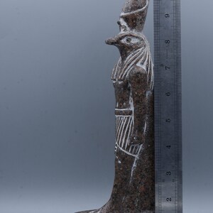 K&ouml;nnte beinhalten: Eine braune und wei&szlig;e Granitstatue eines &auml;gyptischen Gottes mit Falkenkopf. Die Statue ist etwa 25 cm hoch und steht auf einem Sockel mit Hieroglyphen.