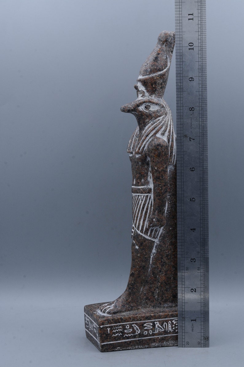 K&ouml;nnte beinhalten: Eine braune und wei&szlig;e Granitstatue eines &auml;gyptischen Gottes mit Falkenkopf. Die Statue ist etwa 25 cm hoch und steht auf einem Sockel mit Hieroglyphen.