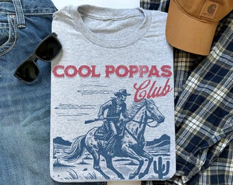 May include: Gray t-shirt with a graphic of a cowboy riding a horse and the text "Cool Poppas Club".