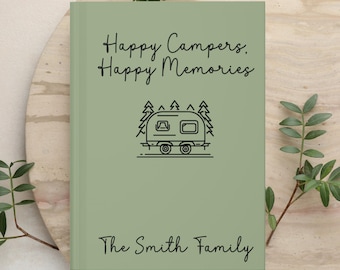 May include: A sage green hardcover book featuring the black text Happy Campers, Happy Memories at the top, a black line art illustration of a camper trailer surrounded by pine trees in the center, and the text The Smith Family at the bottom.