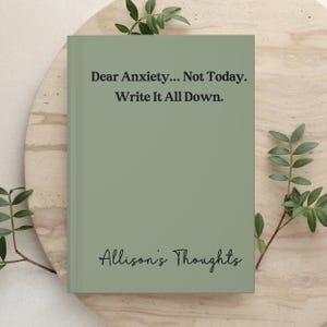 May include: A sage green journal with a hard cover featuring the black printed text Dear Anxiety... Not Today. Write It All Down. at the top and the black cursive text Allison's Thoughts at the bottom, centred on the front cover surface.
