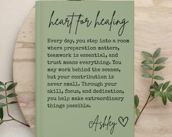 May include: A sage green rectangular journal with the title heart for healing in black script. The text reads: Every day, you step into a room where preparation matters, teamwork is essential, and trust means everything. Signed Ashley with a heart.