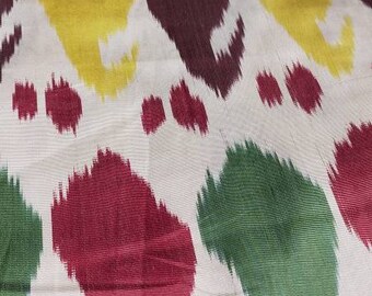 Può includere: Tessuto bianco con un motivo ripetitivo di forme astratte in rosso, verde, giallo e blu. Le forme ricordano i disegni paisley o ikat.