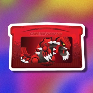 Peut inclure: Une cartouche rouge Game Boy Advance avec un monstre rouge et noir sur le devant. La cartouche porte l'inscription "GAME BOY ADVANCE" en haut.