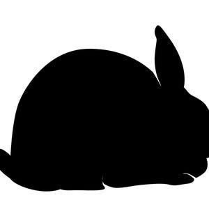 May include: A black silhouette of a rabbit in a resting position. The rabbit's body is rounded, with one ear upright and the other folded down. The image is a simple, graphic representation of a bunny.