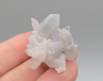 Puede incluir: Un grupo de cristales de cuarzo blanco con un aspecto translúcido. Los cristales están agrupados en una formación aleatoria.
