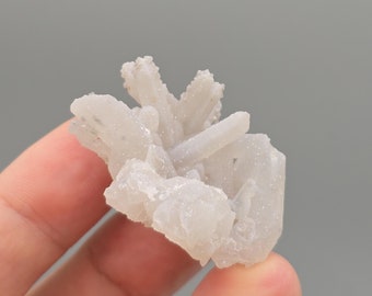 Puede incluir: Un grupo de cristales de cuarzo blanco con una superficie rugosa y texturizada. Los cristales están dispuestos en un patrón aleatorio y orgánico.