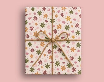 Op de afbeelding: Een rechthoekig cadeau verpakt in off-white papier met een herhalend patroon van kleine bloemen in olijfgroen, mosterdgeel en zachtroze tinten. Het pakket is vastgebonden met een dun, natuurlijk bruin jute touw in een strik.