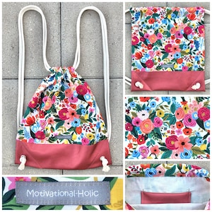 Puede incluir: Mochila con cordón con un vibrante estampado floral en rosa, rojo, azul y amarillo. La sección inferior es de color rosa empolvado. Se ven correas de cuerda blancas y el texto "Motivational-Holic".