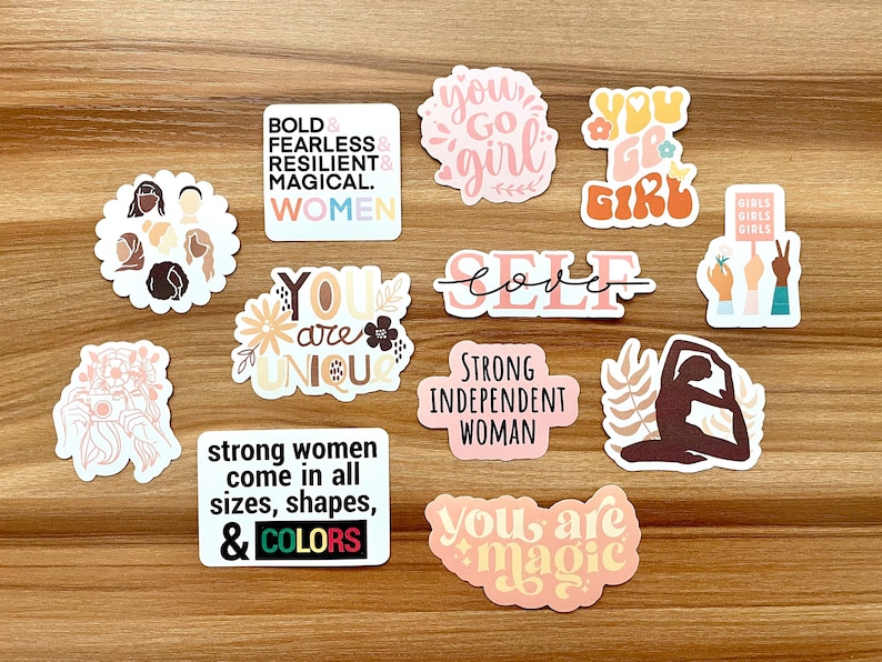 May include: A collection of colorful stickers with empowering messages and illustrations. Designs include text like "Bold & Fearless," "You Go Girl," and "Strong Independent Woman." The stickers feature floral and abstract designs.