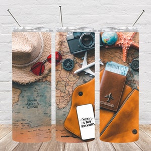 May include: A travel-themed tumbler featuring a world map design. The tumbler showcases a straw hat, red sunglasses, a vintage camera, a compass, a toy airplane, a passport, and a phone with the text "Signs to New Adventures."
