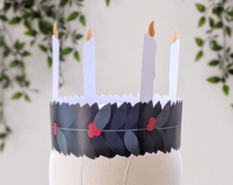 May include: A paper advent crown with four white candles and a black and green holly wreath with red berries.