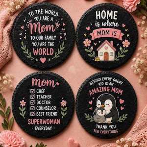 May include: Four black slate coasters with white and pink text and illustrations. One says "To the world you are a Mom." Another says "Home is where Mom is." The third says "Mom Superwoman Everyday." The last says "Behind every great kid is an amazing Mom."