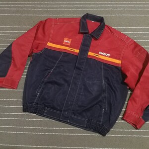 May include: A red and blue work jacket with the word "ENEOS" printed on the front in white and orange lettering.