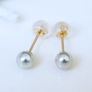 May include: A pair of gold earrings with a 4-5mm natural blue pearl on each earring. The earrings are made of 18 karat gold.