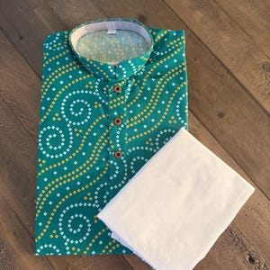 May include: A green and white patterned shirt with a mandarin collar and button closure. The shirt is paired with a white plain fabric.