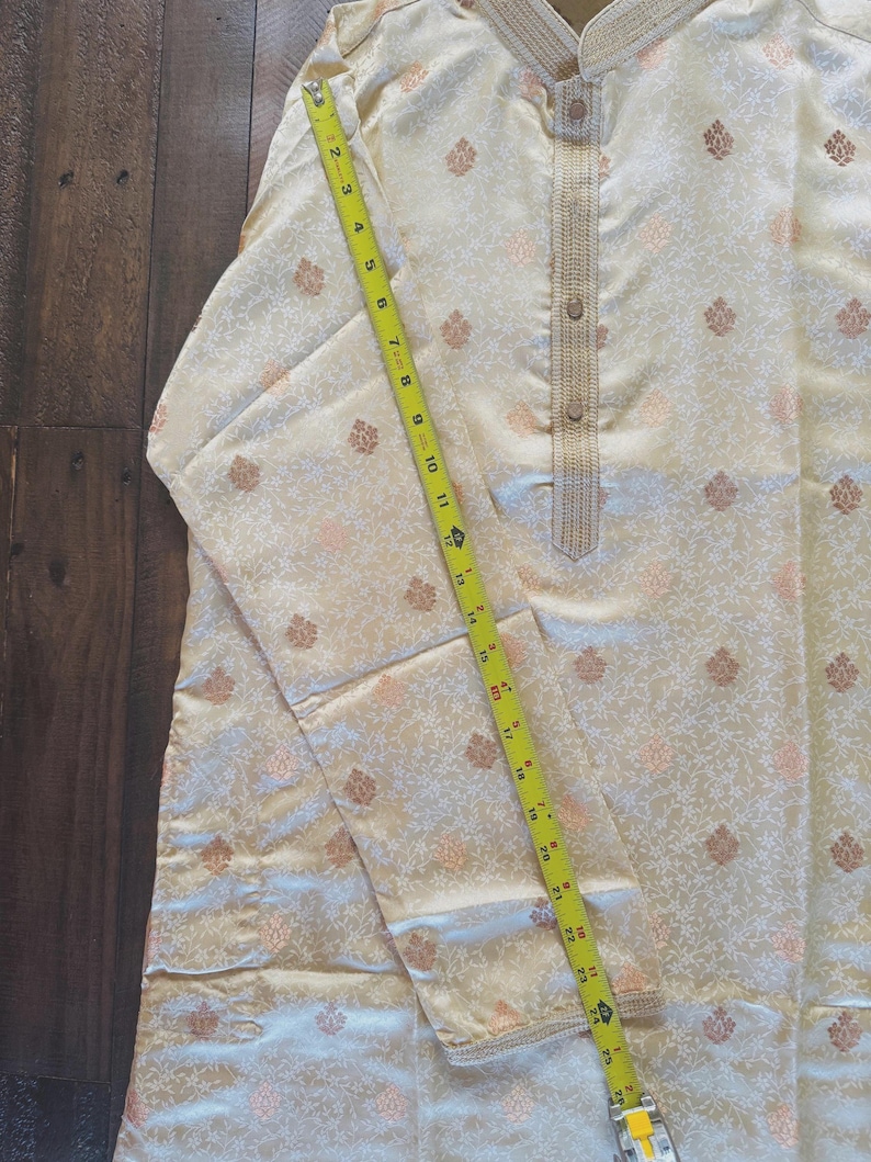 Pu&ograve; includere: Kurta color crema con motivo floreale e colletto alla coreana. L'indumento a maniche lunghe ha una chiusura frontale con bottoni ed &egrave; misurato con un metro a nastro giallo. La kurta &egrave; lunga circa 63,5 cm.