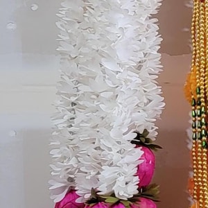 May include: A vertical garland with white floral elements and bright pink flower buds. The garland is decorated with multiple pink flower buds and white floral accents, creating a visually appealing decorative piece.