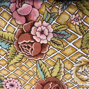 May include: A brown and white floral fabric with a repeating pattern of flowers and leaves on a gold and white grid background.
