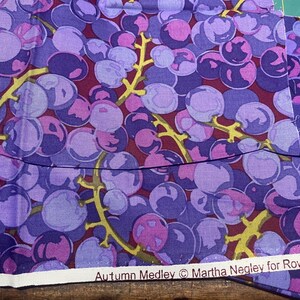 May include: Fabric featuring a grape cluster design in purple, pink, and burgundy hues, with yellow stems. The text "Autumn Medley © Martha Negley for Rowan" is visible.