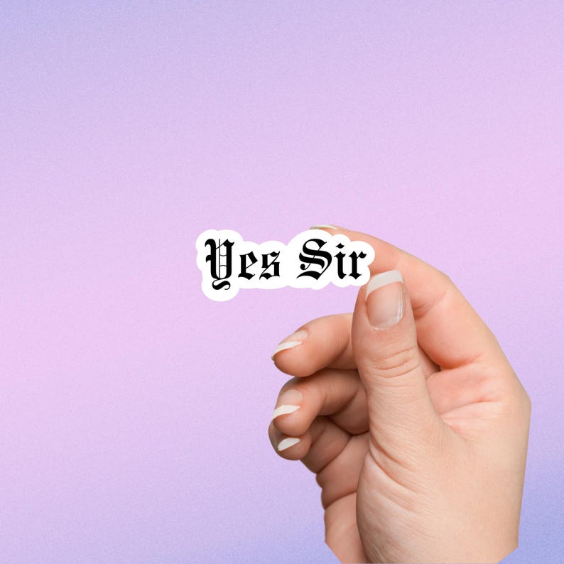 May include: A white sticker with black text that reads "Yes Sir" in a gothic font. A hand is holding the sticker.