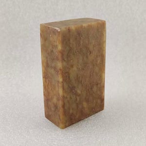 Könnte beinhalten: Ein rechteckiger Block aus braunem und beigefarbenem Stein mit einem marmorierten Muster. Der Stein ist glatt und poliert.