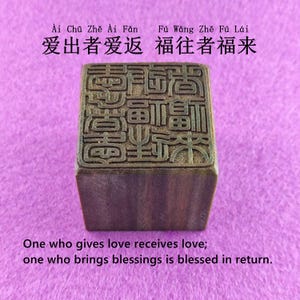 Puede incluir: Un sello de madera con caracteres chinos y el texto en inglés "One who gives love receives love; one who brings blessings is blessed in return." El sello es cuadrado y tiene un diseño detallado.