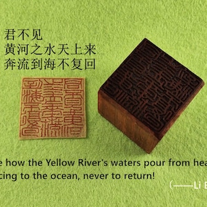 Puede incluir: Un sello de madera marrón con intrincadas tallas y forma rectangular, junto a una impresión estampada. El texto de la imagen dice: "¡Mira cómo las aguas del río Amarillo fluyen del cielo, corriendo hacia el océano, para no volver jamás!" por Li Bai.