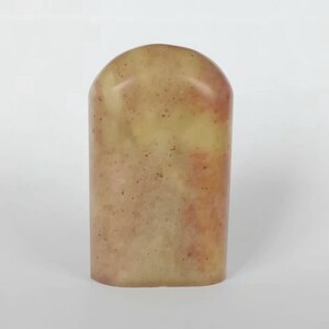 May include: A light brown and red stone seal with a rounded top and a rectangular base.