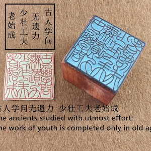 Puede incluir: Dos sellos de madera con caracteres chinos. Un sello es rojo y rectangular, el otro es un sello cuadrado con una parte superior azul y una base de madera. El texto de la imagen dice: "Los antiguos estudiaron con el máximo esfuerzo; La obra de la juventud sólo se completa en la vejez."