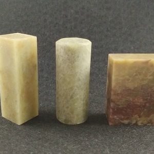 May include: Three rectangular blocks of stone, each with a different pattern and colour. The first block is a light green with a smooth surface. The second block is a light green with a rough surface. The third block is a light green with a brown and red pattern.