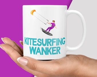 May include: White ceramic mug with a blue and white graphic of a person kitesurfing. The text "KITESURFING WANKER" is printed in blue on the mug.