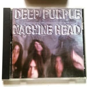 May include: A Deep Purple "Machine Head" CD case. The album title and band name are embossed in silver on a gray background. The cover features a blurred image of the band members.