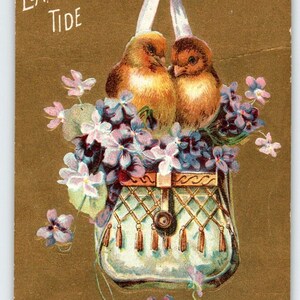 May include: A vintage Easter postcard featuring two yellow chicks perched on a white purse with purple and white flowers. The text "Happy Easter Tide" is printed in gold lettering.