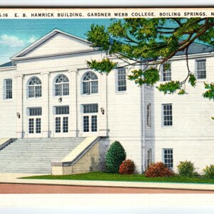 May include: Vintage postcard featuring the E. B. Hamrick Building at Gardner Webb College in Boiling Springs, N.C. The white building has a classical design with columns, arched windows, and a grand staircase. Green foliage frames the top right corner.
