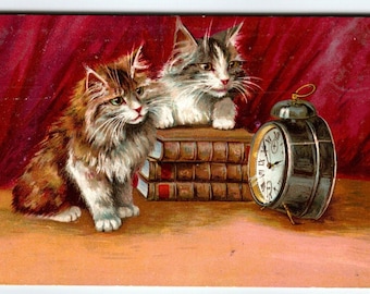 子猫が本に寄りかかって時計を見つめているヴィンテージ猫のポストカード M Boulanger M&W 1907