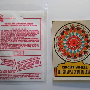 May include: Vintage decalcomania set featuring a colorful circus wheel design with the text "Circus Wheel The Greatest Show on Earth." Includes a clear plastic bag with instructions and a price of 15¢.