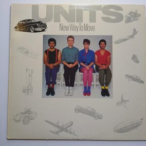 May include: Album cover for "Units - New Way To Move." The cover features the band members seated, with a vintage car graphic and other illustrations. The band name is in large gray letters at the top.