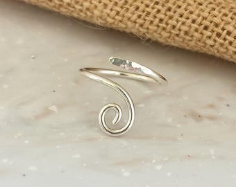 May include: A silver ring with a hammered finish and a spiral design.