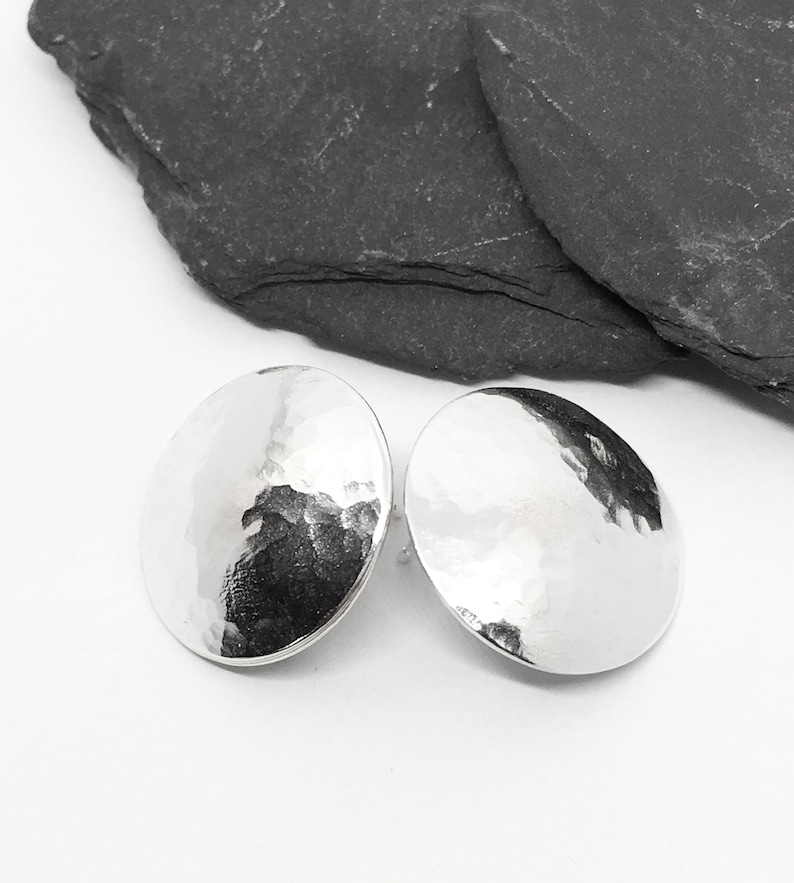 May include: A pair of silver hammered disc earrings. The earrings are round and have a textured surface.