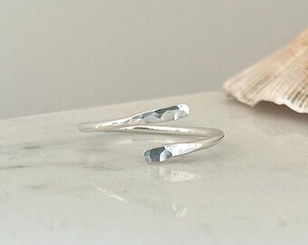 May include: A silver hammered ring with a twisted design. The ring is open and adjustable.