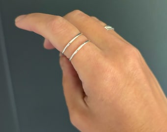 May include: Two thin silver rings worn on a finger.